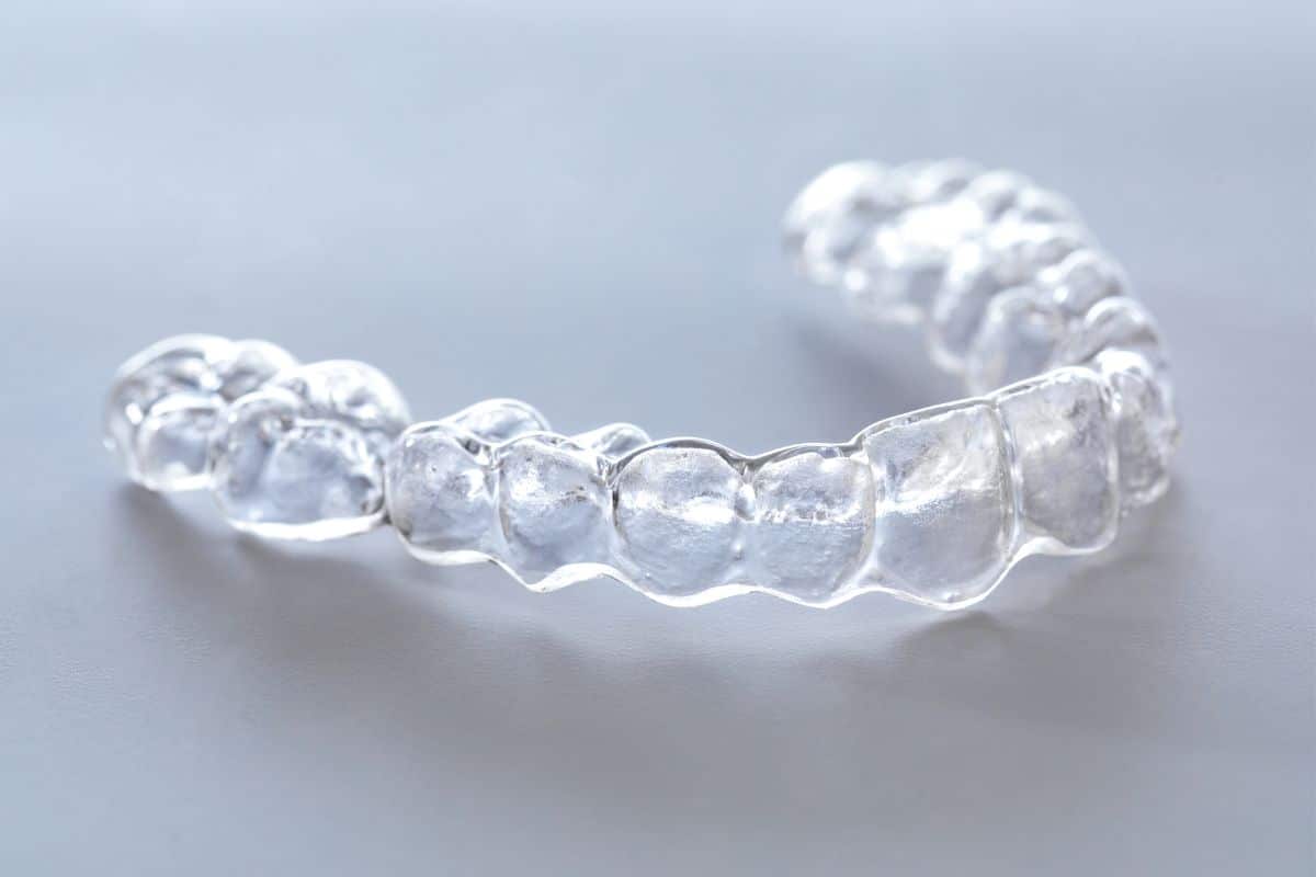Close-up of clear Invisalign aligners placed on a white table.